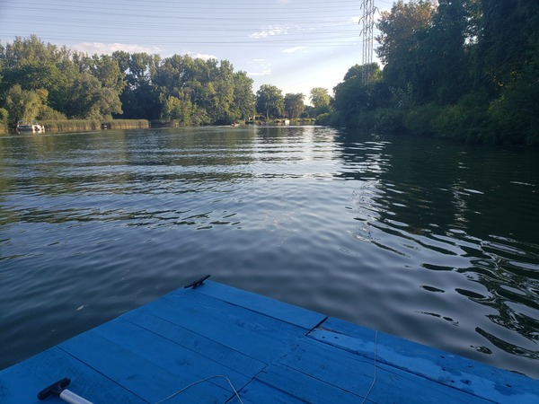 A view of the Erie canal with a sliver of the boat’s deck in frame towards the bottom